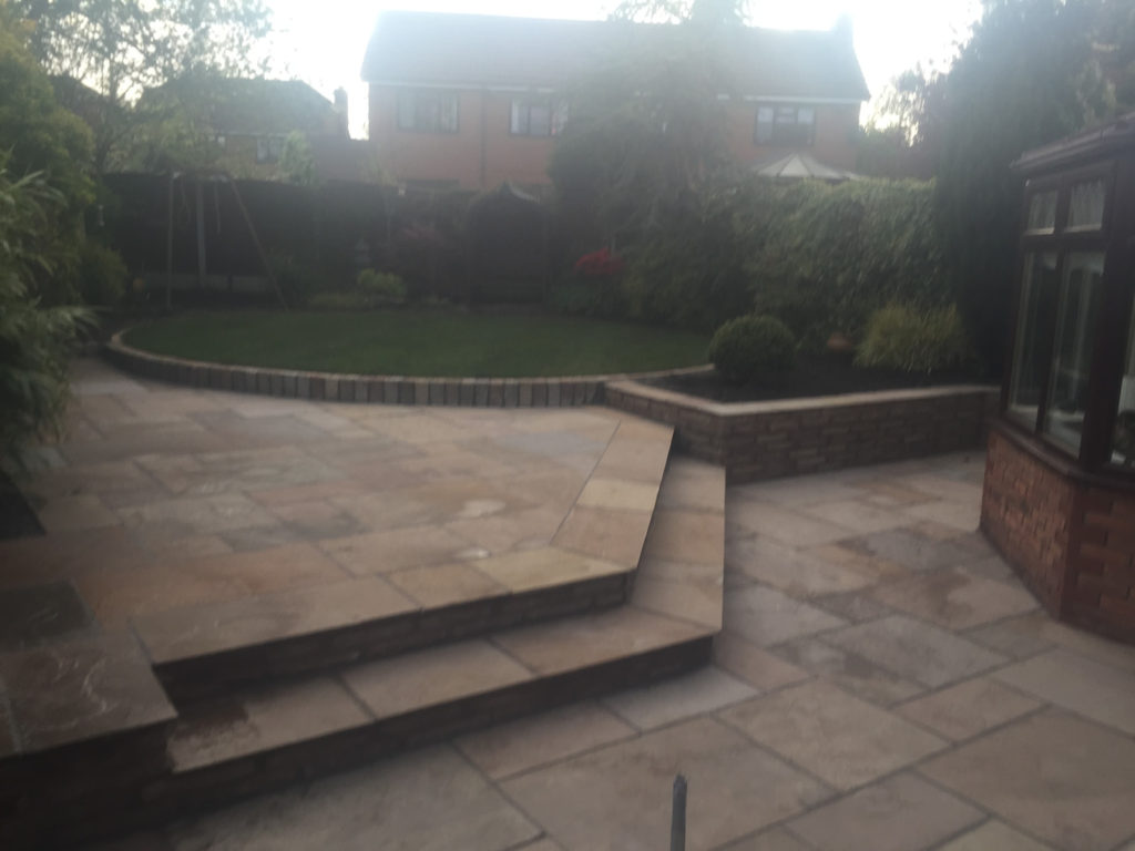 Split-level sandstone patio with steps and a brick raised bed