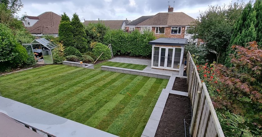 Newly turfed striped lawn with raised beds and a summer house